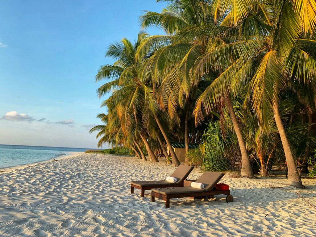 Lounge chairs on the beach at the W Hotel luxury resort in the Maldives during sunset.
