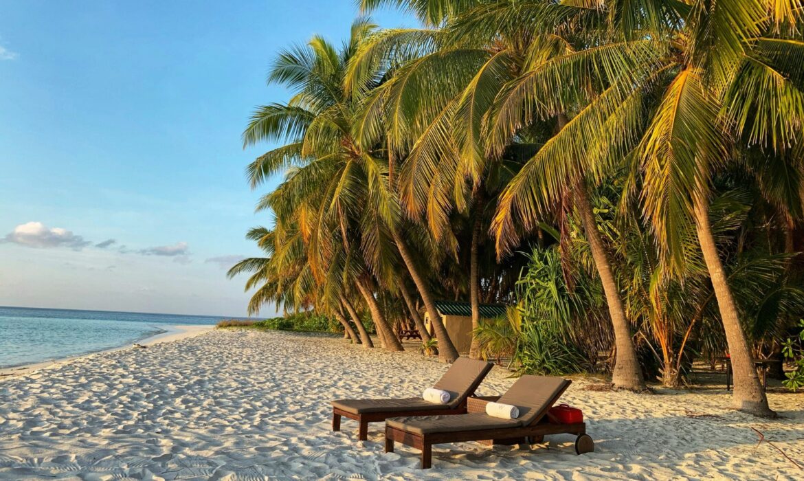 Lounge chairs on the beach at the W Hotel luxury resort in the Maldives during sunset.
