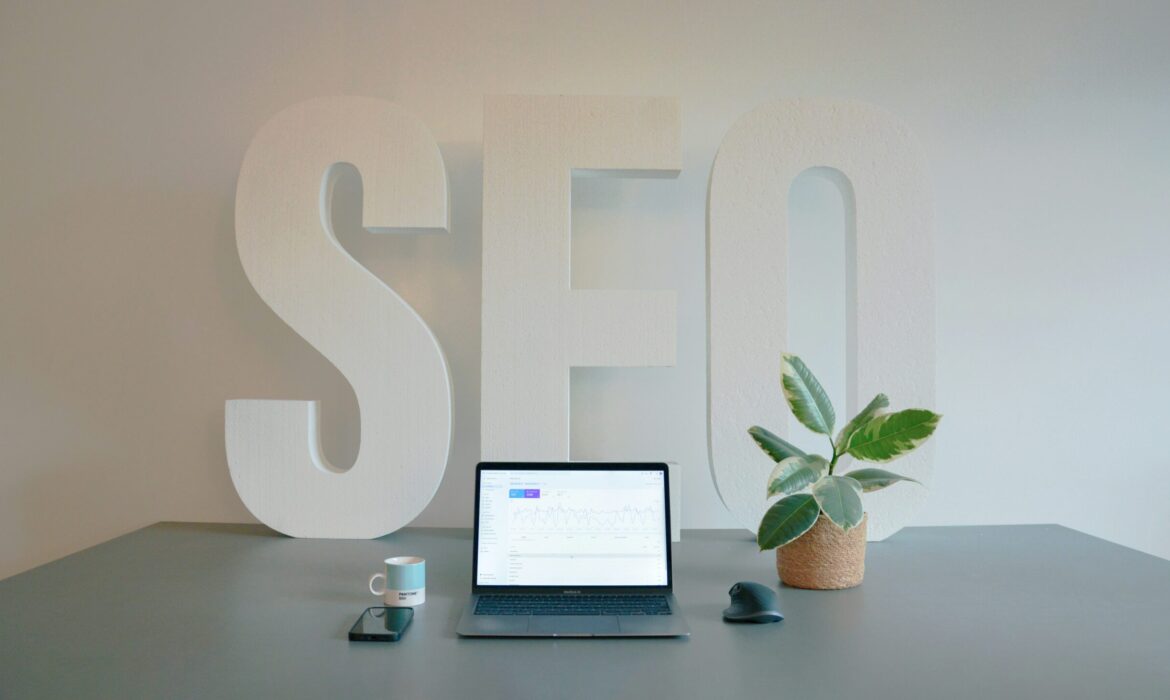 Modern and organized workspace in an SEO agency, featuring a sleek office desk with large 'SEO' letters in the background. The desk is ready for productivity, with an espresso, a mobile phone, and a small plant neatly arranged. The absence of a person creates a calm, inviting environment, perfect for focused work in the digital marketing space.